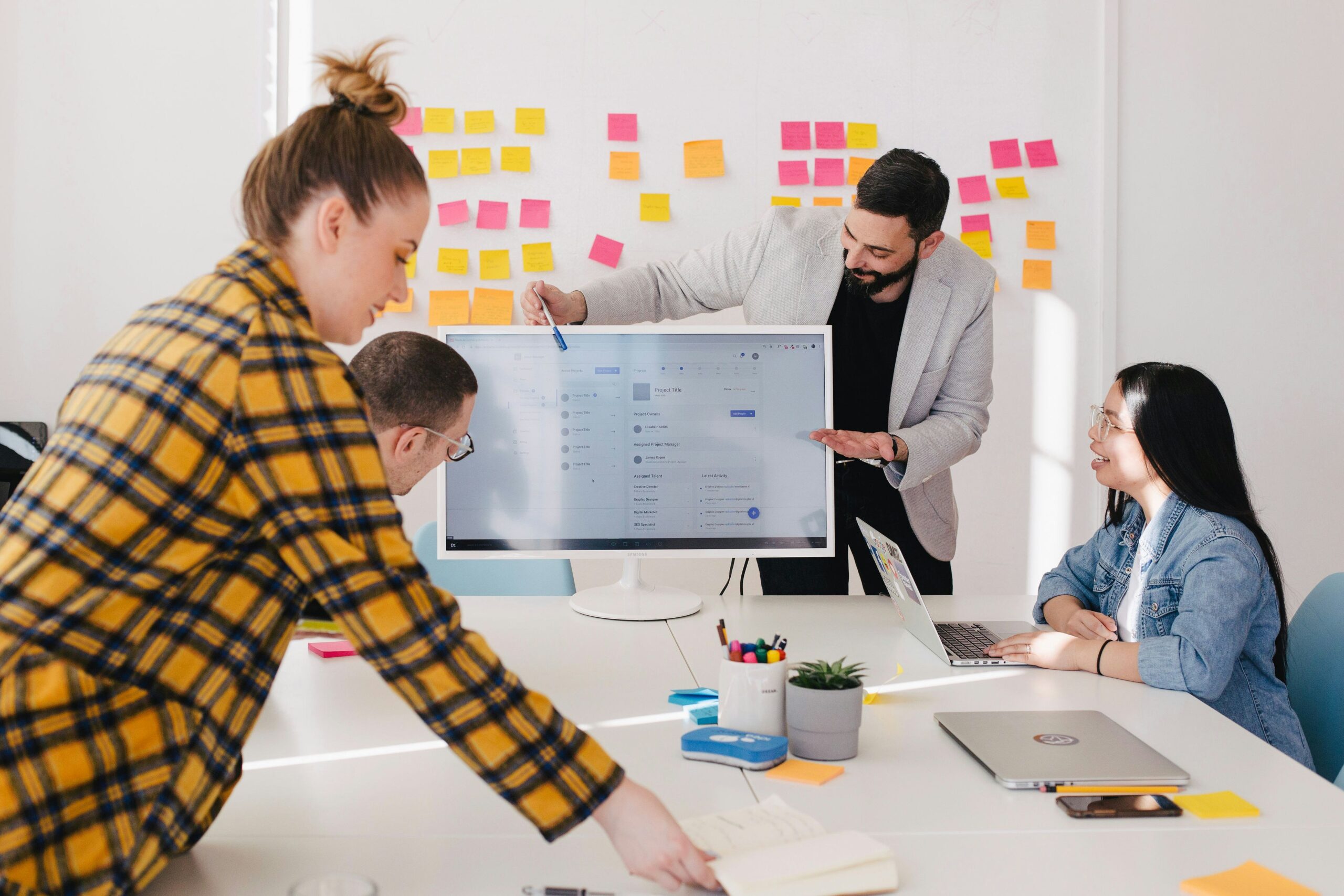 Team of professionals in a brainstorming session, discussing business strategies and communication goals with a digital display.